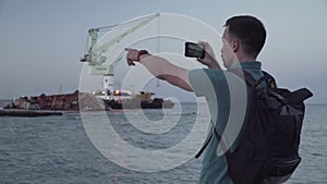 Man blogger records video blog on mobile phone for social media about accident of wreck tanker Delfi with oil in Odessa