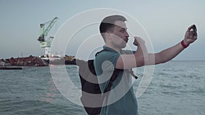 Man blogger records video blog on mobile phone for social media about accident of wreck tanker Delfi with oil in Odessa