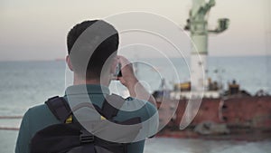 Man blogger records video blog on mobile phone for social media about accident of wreck tanker Delfi with oil in Odessa