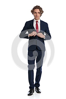 Man with blond hair buttoning his suit and being confident