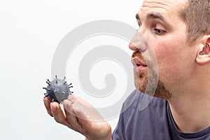 Man blow away the grey model of virus in his hands