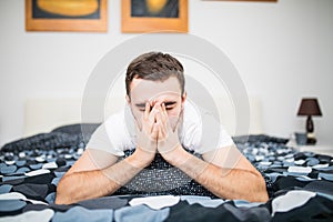 Man blowing his nose while lying sick in bed at home