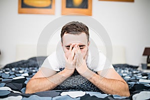 Man blowing his nose while lying sick in bed at home