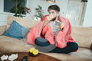 Man blowing his nose while lying sick at home