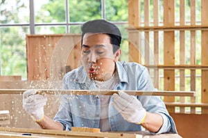 Man blowing sawdust out of timber wood.