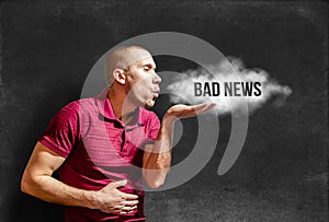 A man blows a cloud of bad news from his palm