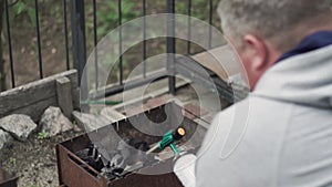 a man blows a fire in the brazier with a gas burner