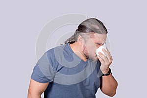 A man blows his nose forcibly into a tissue paper. Dealing with a cold, rhinitis or allergy