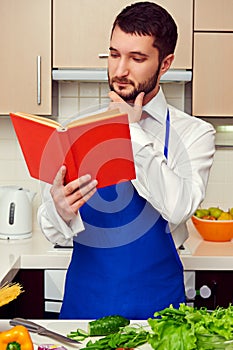 Man in blue apron reading cookbook