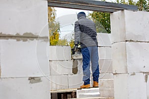 A man in a blue jacket and blue pants is working on a wall