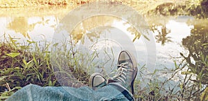 Man in blue jeans wearing old sneakers sitting on green grass.vacation and relax tarn at the garden