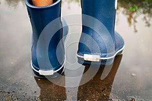 Man in blue rubber boots walking through the puddle
