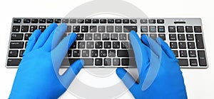 A man in blue rubber gloves is typing on the keyboard. Disinfection in public places, the fight against the virus, coronavirus.