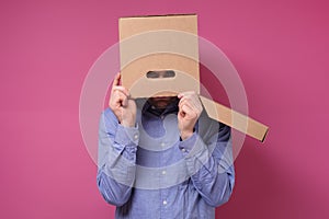 Man in blue shirt with a brown paper box on his head, hiding from job stress.