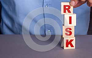 A man in a blue shirt composes the word RISK from wooden cubes vertically