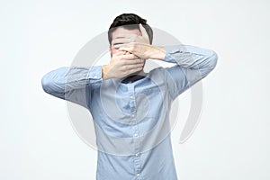 Man in blue shirt covered his face with his hands