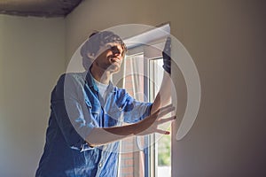 Man in a blue shirt does window installation