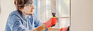 Man in a blue shirt does window installation BANNER, LONG FORMAT