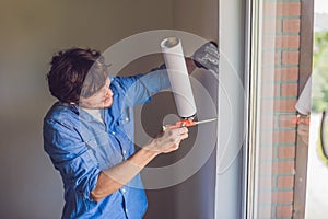 Man in a blue shirt does window installation