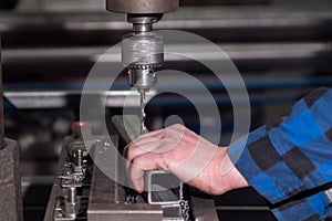 A man in a blue shirt drills a hole in the details at a small enterprise