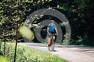 Man in blue shirt, helmet and sunglasses riding on bicycle