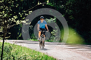 Man in blue shirt, helmet and sunglasses riding on bicycle
