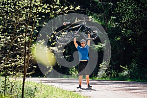 Man in blue shirt, helmet and sunglasses riding on bicycle