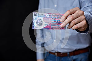Man with blue shirt holding Hong Kong dollars