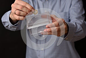 Man with blue shirt holds symbolic house, piggybank