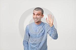 Man with blue shirt saying hello, waving a hand