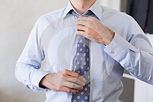 Man in blue shirt straightens his tie