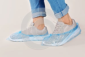 Man with blue shoe covers worn over sneakers on white background