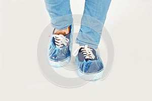 Man with blue shoe covers worn over sneakers on white background