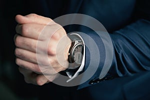 A man in a blue suit and a classic wooden mechanical watch