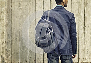 Man in blue suit and jeans with leather backpack