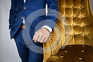 Man in blue suit standing beside sofa