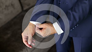 Man in the blue suit straightens his sleeves.