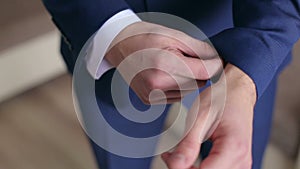 Man in blue suit straightens his sleeves, close-up