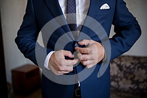 Man in blue suit and tie fastens button