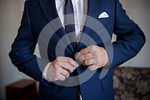 Man in blue suit and tie fastens button