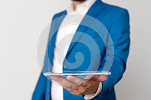 Man in the blue suite and white shirt holds mobile phone in the hand. Business concept with businessman and mobile phone