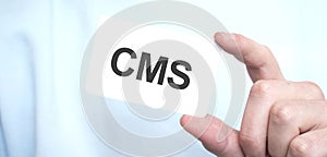 Man in blue sweatshirt holding a card with text CMS,business concept