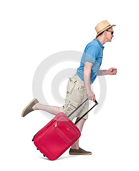 A man in a blue T-shirt, hat and shorts runs and pulls a red suitcase behind him. Isolated on white background