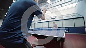 Man in blue T-shirt playing a ping-pong with woman at the court