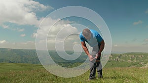 Man in blue t shirt unzips low part of pants and makes shorts on plateau Bermamyth. Greatness of wild nature.