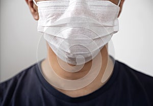 Man in blue t-shirt wearing wearing white surgical protective hygiene mask on face  close up shot