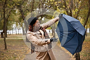 Man with blue umbrella caught in gust of wind outdoors