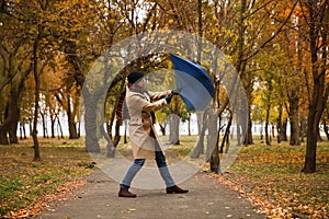 Man with blue umbrella caught in gust of wind outdoors