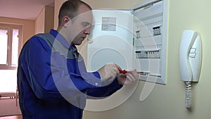 Man in blue uniform working on a circuit breaker at flat house