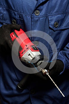 A man in a blue work suit holding a drill